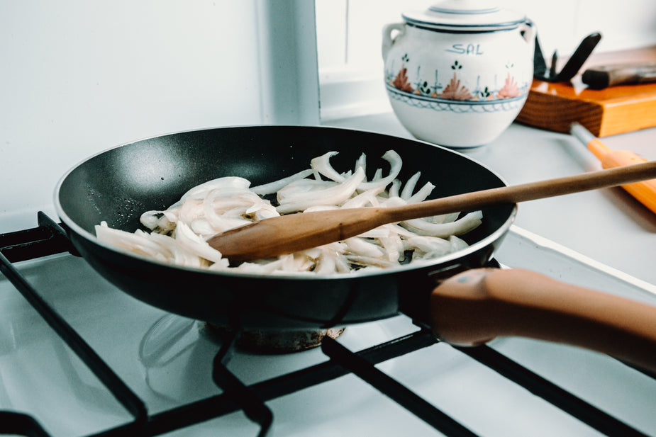 White-onions-being-sauteed-in-a-pan-with-wooden-spoon